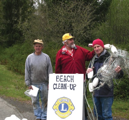 Lions Emil Person and Roy Morris with their helper, Paul Blake, clean up debris along the Strait of Juan de Fuca in Washington.