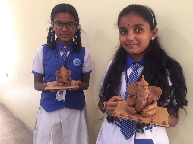 Two students present their versions of the environmentally friendly clay Ganesha idols.