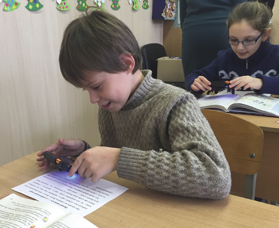 A vision-impaired student at an orphanage in Ukraine uses one of the 45 electronic magnifiers provided by Lions to help keep students on track.