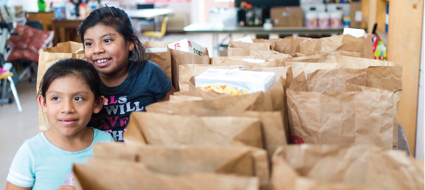 Girls peek into the packages at the food pantry, hoping to find their favorite goodies inside. PHOTOS BY ZACK WITTMAN