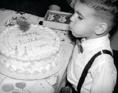A young Haynes blows out some birthday candles while sporting what would become his signature look—a tidy, hand-tied bow tie.