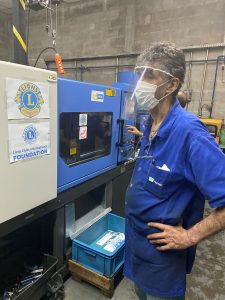 Man stands at machine making Lion face shields