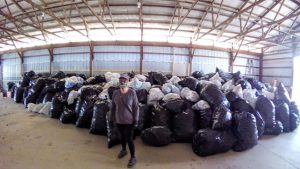 Woman standing in front of bags of cans