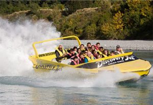 Yellow boat filled with people cuts through a wave