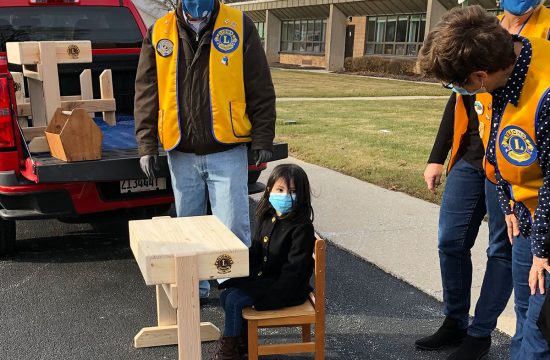 Girl sits at a new school desk built for her by Agawam Lions Club members.