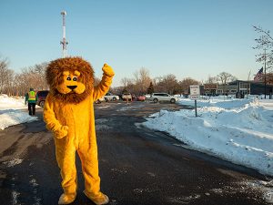 Person in Lion costume waves.