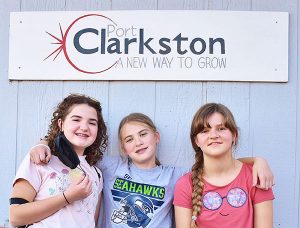 Three girls in front of Clarkson sign