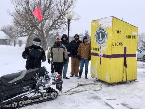 Lions Clubs INternational membes stand next to yellow shack