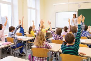 children raise hands in a classroom