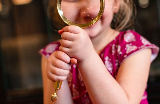 Little girl holds magnifying glass up