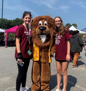 Two girls stand with person in Lion costume