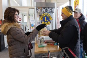 Lions club member hands over bag of popcorn
